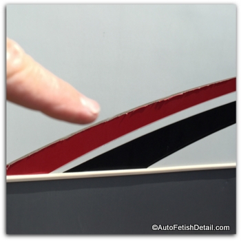 Red and black decals peeling from the side of RV peeling RV decals